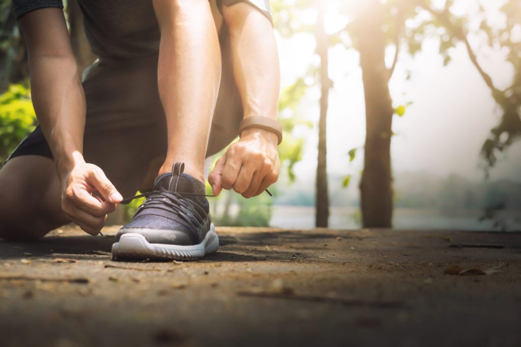 A person tying their shoe laces on the ground.
